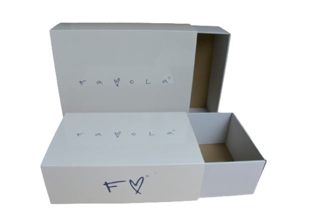 Pudełko w kolorze białym z logotypem "Favola", otwarte w sposób pokazujący dodatkową, mniejszą szufladkę wewnątrz.